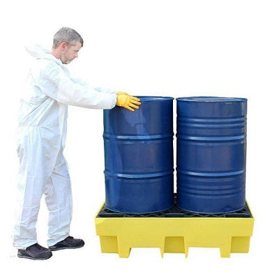 a man standing beside spill pallet 2 drums